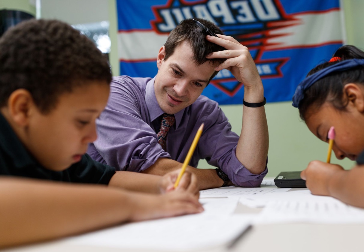 Photo of teacher working with two young students