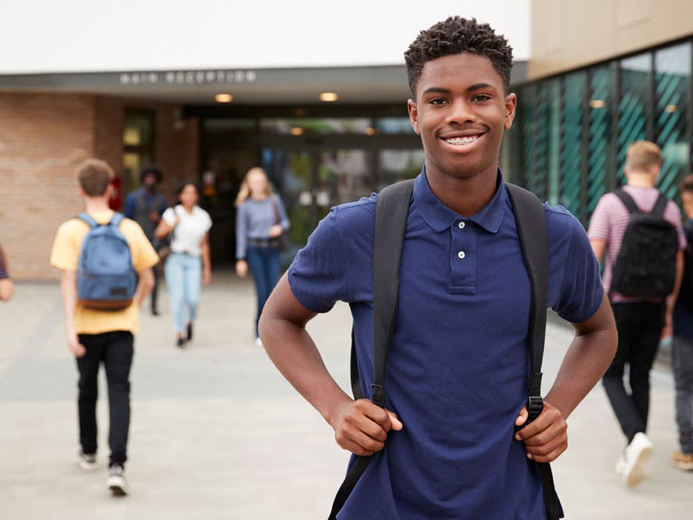 Student smiling in front of school