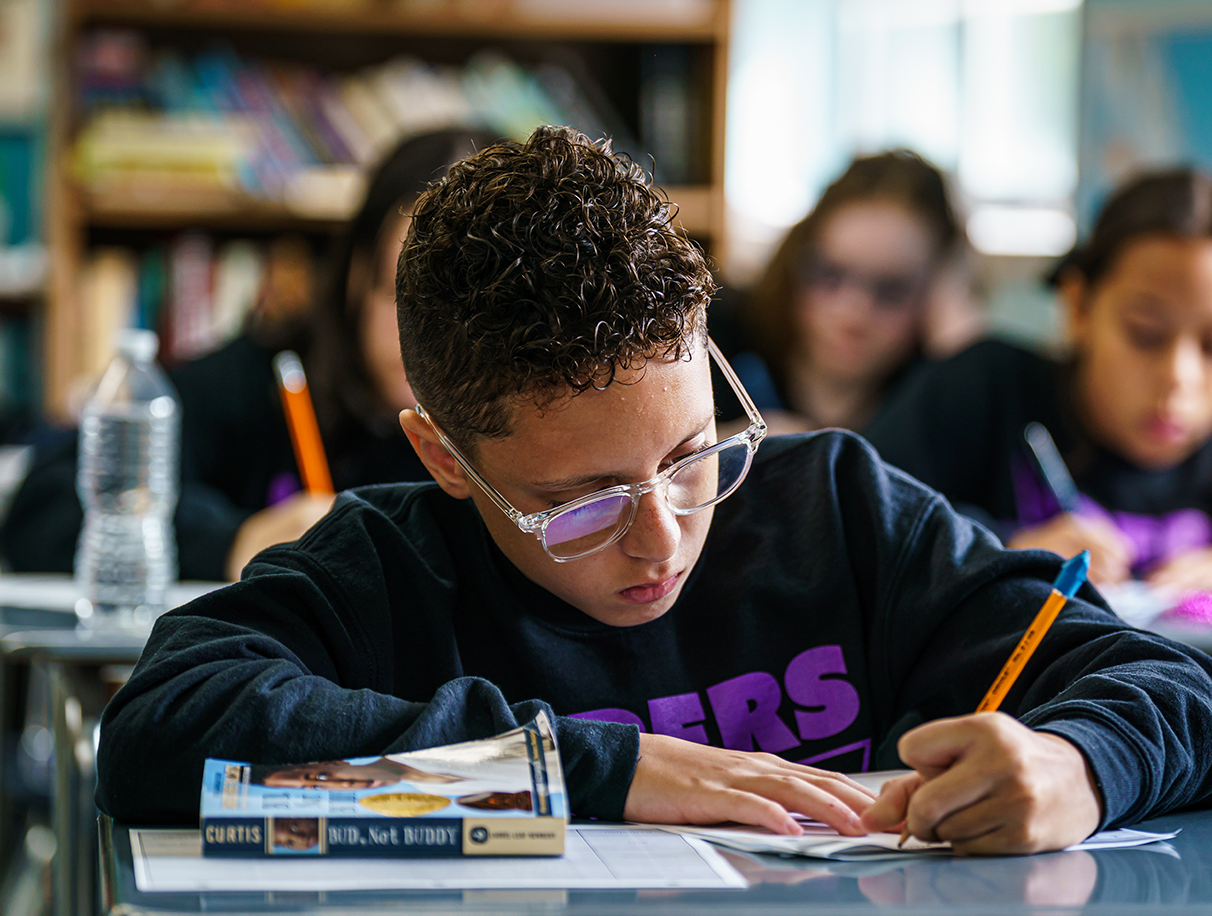 boy with glasses writing