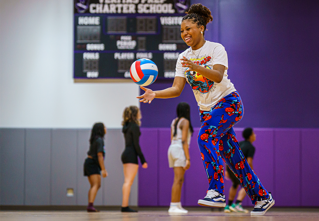 female athlete throwing a volleyball in gymnasium