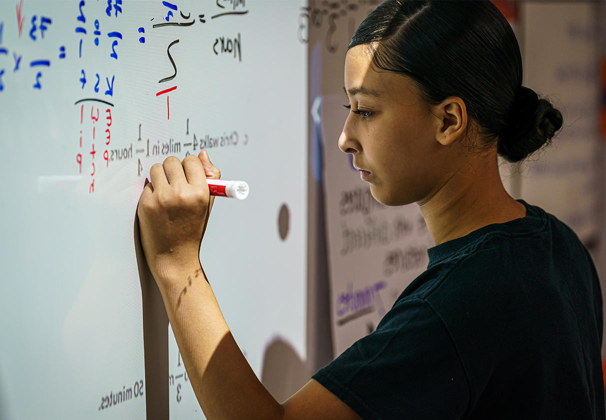 female student writing on whiteboard